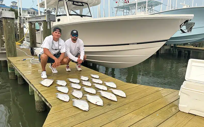 Cross Ferrara and a friend displaying their flounder catch next to their Regulator 41 at the dock