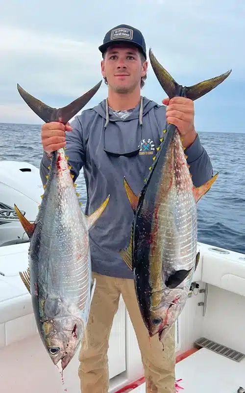 Cross Ferrara holding two yellowfin tuna caught during an offshore fishing trip aboard the Regulator 41